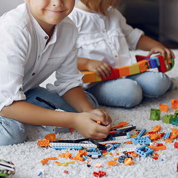 Spielende Kinder auf einem Teppich mit Legosteinen